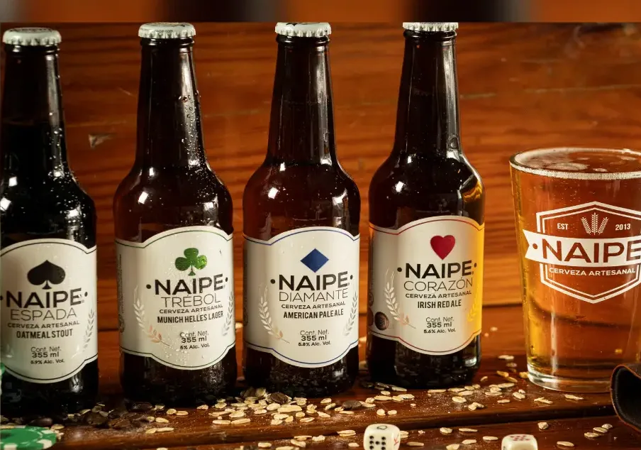 Cuatro cervezas Naipe junto a un vaso