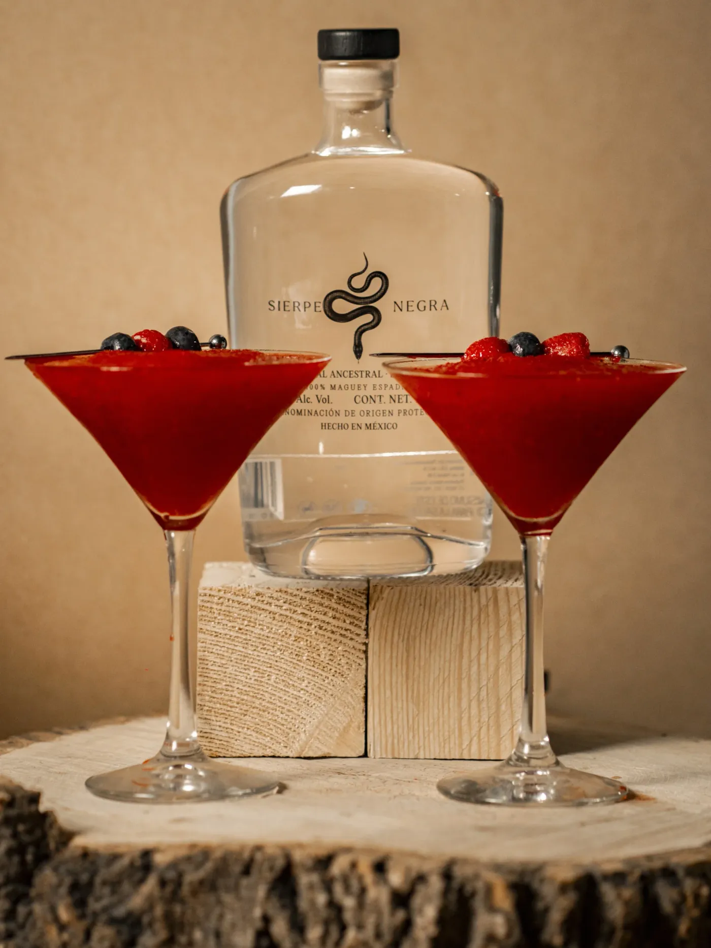 Dos cócteles rojos con mezcal Sierpe Negra sobre una base de madera
